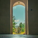 A door frame open to a forest with blue sky. Easy to relax and trust in time.