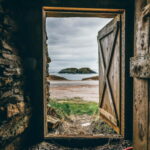 A door frame open to a beach with cloudy sky. Easy to trust in time here too.