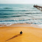 Alleingeborener Zwilling auf Stuhl an Strand wartet auf den Kursabend und schaut aufs Meer hinaus